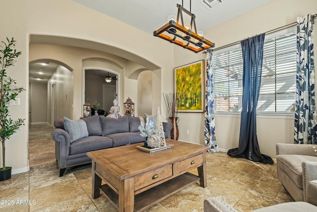 891 W Palo Brea Dr, Litchfield Park, AZ 85340 - living area featuring ceiling fan, visible vents, baseboards, arched walkways, and stone finish floor