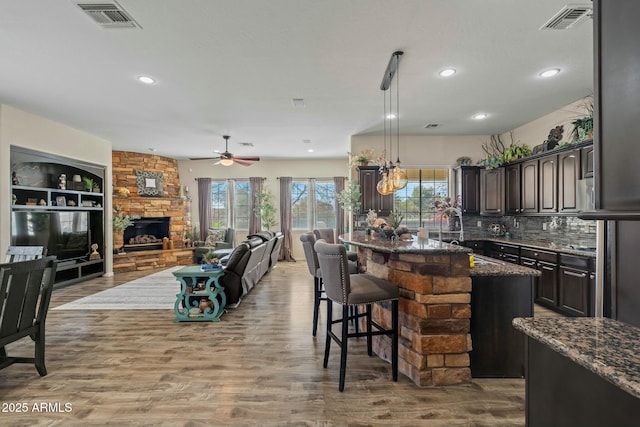 891 W Palo Brea Dr, Litchfield Park, AZ 85340 - kitchen featuring dark stone counters, open floor plan, visible vents, and dark brown cabinetry