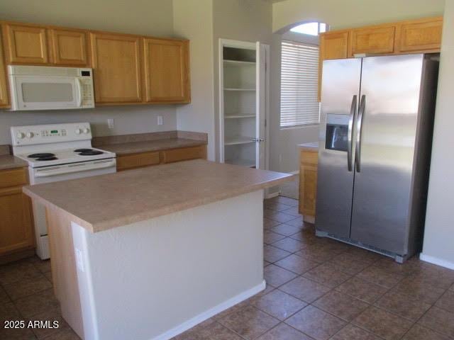 kitchen with a center island, white appliances, light countertops, and tile patterned floors