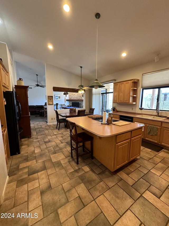 kitchen with a wealth of natural light, vaulted ceiling, a kitchen island with sink, and black appliances