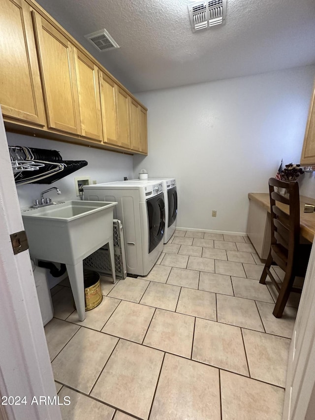 laundry area featuring washer and clothes dryer, light tile patterned flooring, cabinets, and a textured ceiling