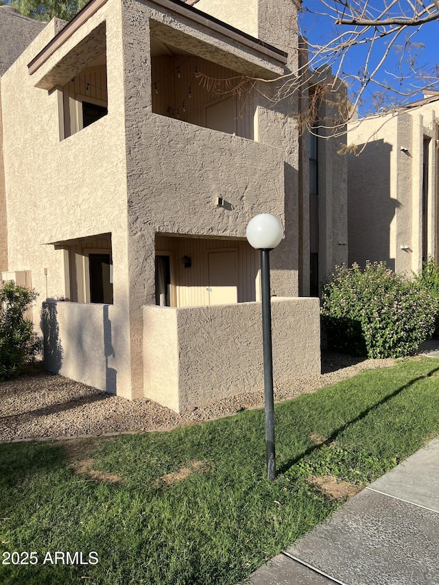 view of home's exterior with a balcony and a yard