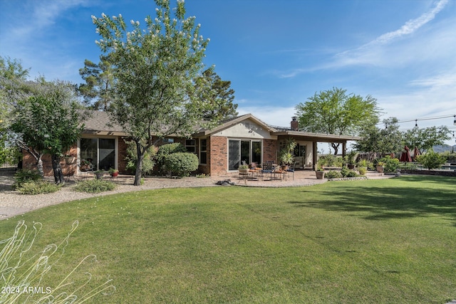 rear view of property featuring a patio and a lawn