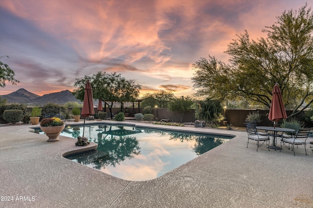 pool at dusk with a mountain view and a patio