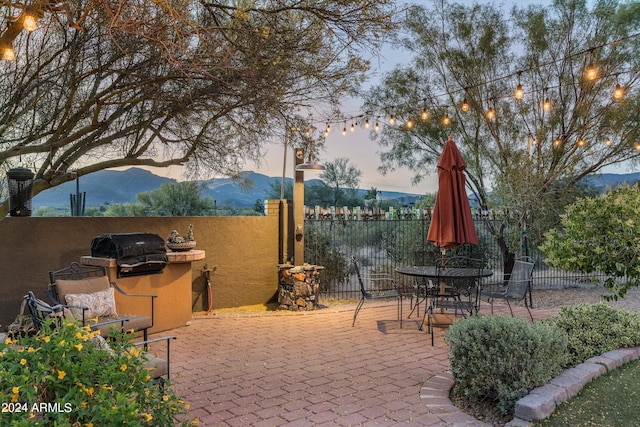 patio terrace at dusk featuring a mountain view and area for grilling