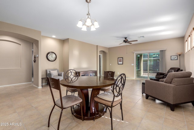 dining space featuring light tile patterned floors, visible vents, arched walkways, baseboards, and ceiling fan with notable chandelier