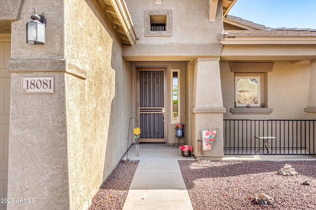 view of exterior entry with a garage and stucco siding