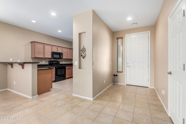 kitchen featuring visible vents, a peninsula, black appliances, a kitchen bar, and recessed lighting