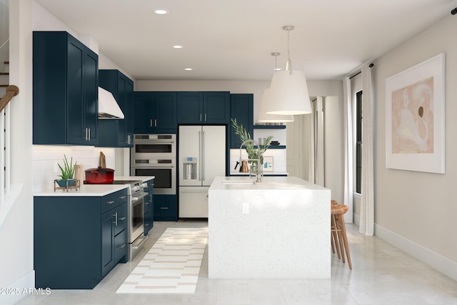 kitchen with pendant lighting, appliances with stainless steel finishes, a kitchen island with sink, range hood, and blue cabinets