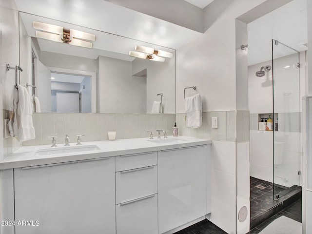 bathroom with double vanity, tiled shower, a sink, and decorative backsplash