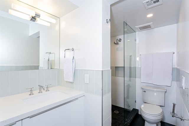 bathroom featuring toilet, an enclosed shower, vanity, and tile walls