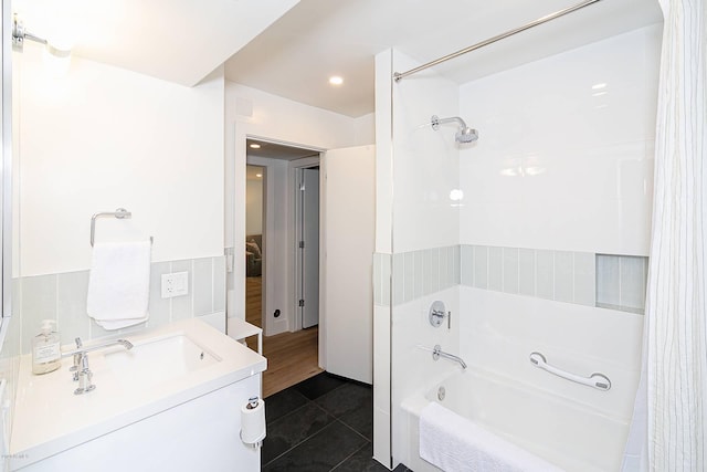 bathroom with wainscoting, tile patterned floors, shower / bath combination with curtain, vanity, and tile walls