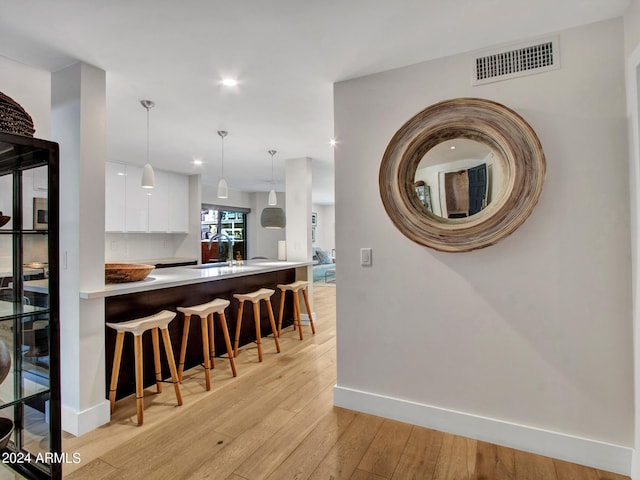 kitchen featuring light wood-style flooring, visible vents, white cabinetry, modern cabinets, and a kitchen bar