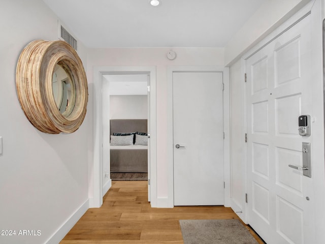 hall featuring light wood-type flooring, visible vents, and baseboards