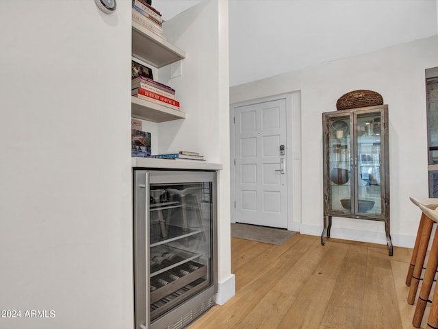 interior space featuring wine cooler, bar, and light hardwood / wood-style flooring