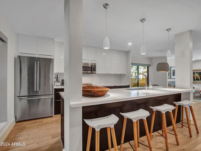 kitchen with stainless steel appliances, white cabinetry, a sink, and modern cabinets