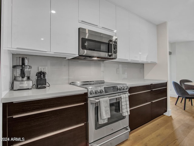 kitchen featuring light countertops, appliances with stainless steel finishes, light wood-style floors, white cabinetry, and modern cabinets