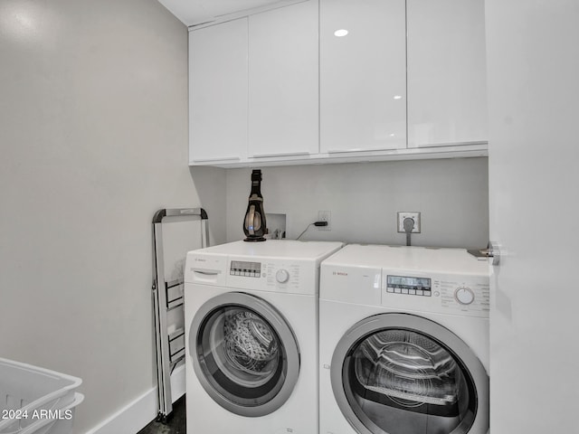 laundry area with baseboards, cabinet space, and washer and dryer