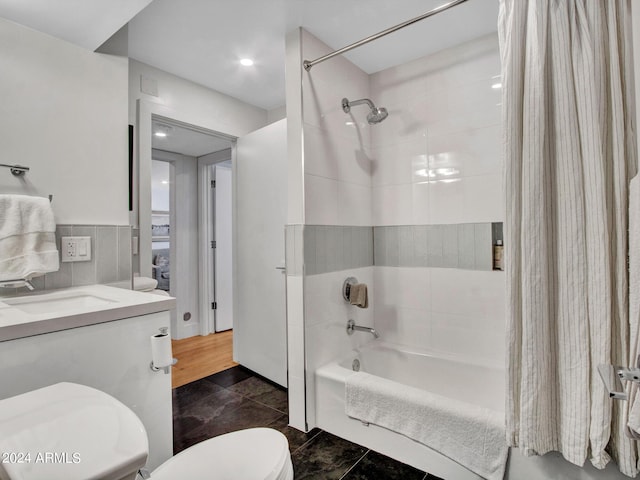 bathroom with toilet, tile walls, shower / tub combo with curtain, and vanity