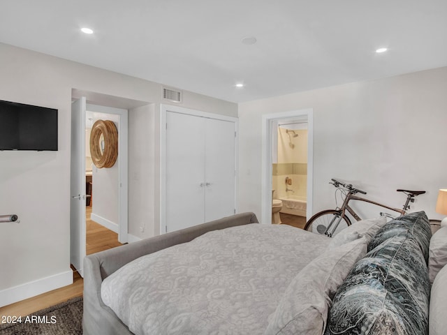 bedroom with recessed lighting, wood finished floors, visible vents, baseboards, and ensuite bath