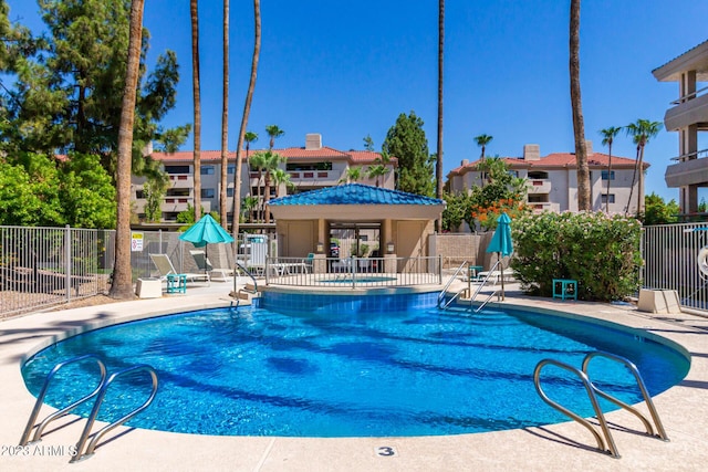 community pool with a patio area and fence