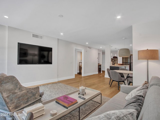 living room with baseboards, visible vents, wood finished floors, and recessed lighting