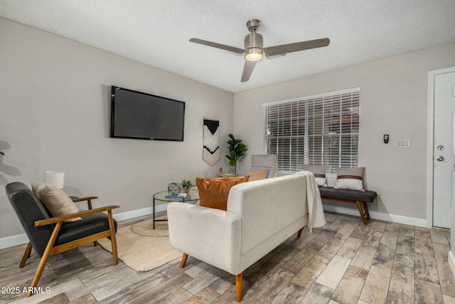 living area featuring light wood-style flooring, a ceiling fan, and baseboards