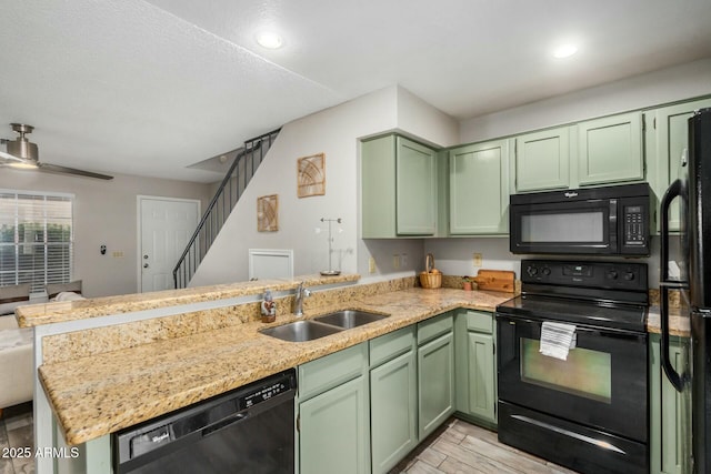 kitchen featuring a sink, a peninsula, black appliances, and green cabinetry