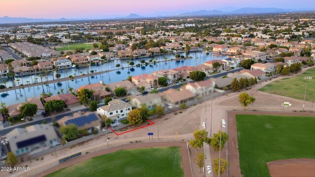 aerial view at dusk featuring a water and mountain view