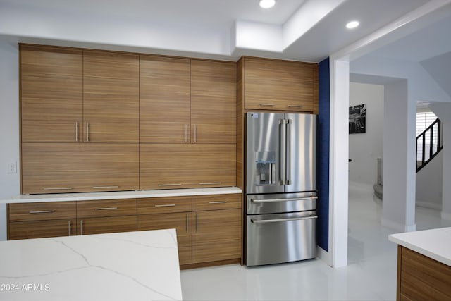 kitchen with light stone countertops and high quality fridge