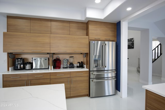 kitchen featuring light stone counters and high end refrigerator