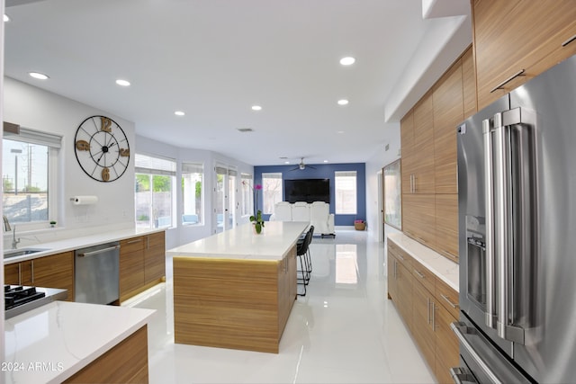 kitchen featuring sink, light tile patterned floors, appliances with stainless steel finishes, a kitchen breakfast bar, and a kitchen island