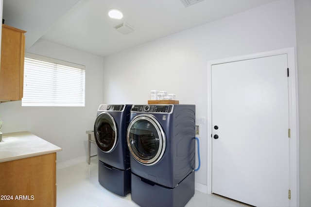 clothes washing area featuring cabinets and washer and clothes dryer