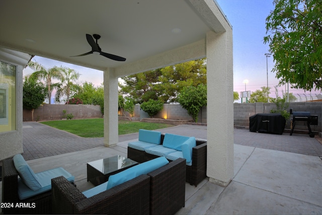 patio terrace at dusk with a lawn, outdoor lounge area, and ceiling fan