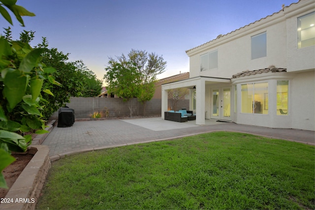 yard at dusk with an outdoor living space and a patio