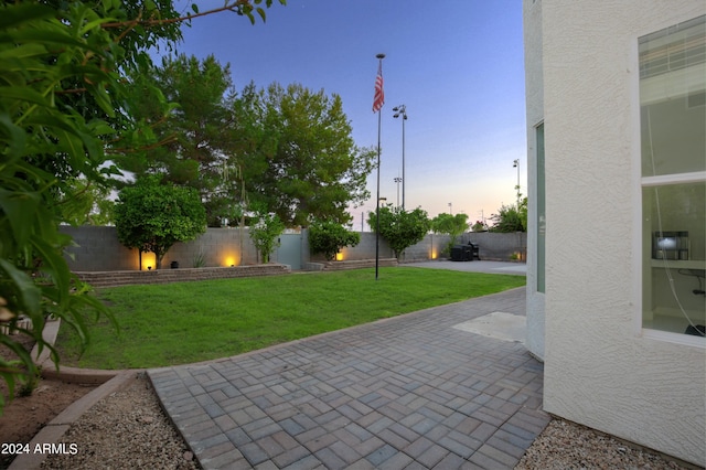 patio terrace at dusk featuring a lawn