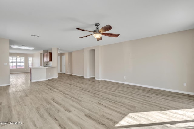 unfurnished living room featuring visible vents, baseboards, light wood-style floors, and a ceiling fan