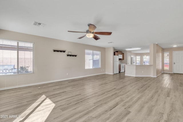 unfurnished living room with light wood finished floors, visible vents, baseboards, and a ceiling fan