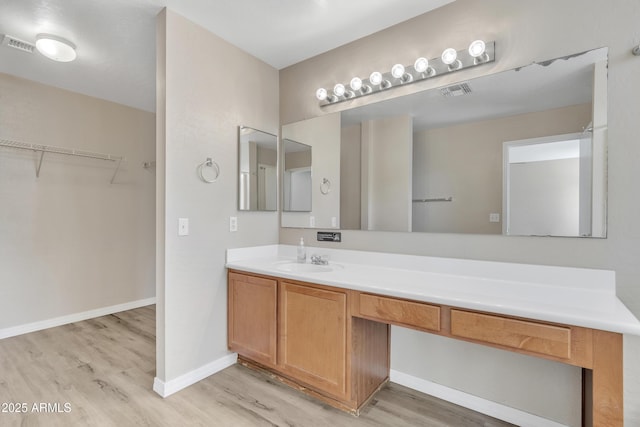 bathroom with visible vents, vanity, baseboards, and wood finished floors