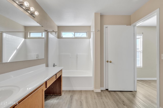 bathroom with baseboards, wood finished floors, bathtub / shower combination, and vanity