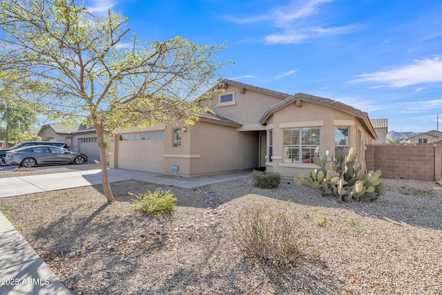 view of front of house with stucco siding, driveway, a garage, and fence