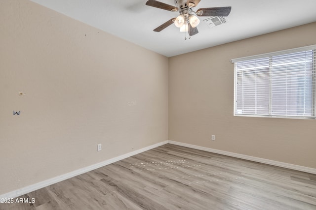 empty room with visible vents, wood finished floors, baseboards, and ceiling fan