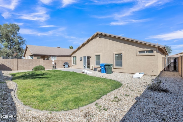 rear view of house with a fenced backyard, stucco siding, a yard, and a patio