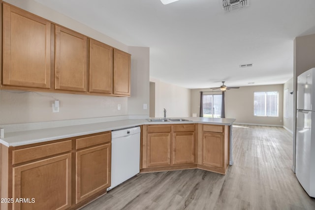 kitchen featuring visible vents, a ceiling fan, a sink, white appliances, and a peninsula