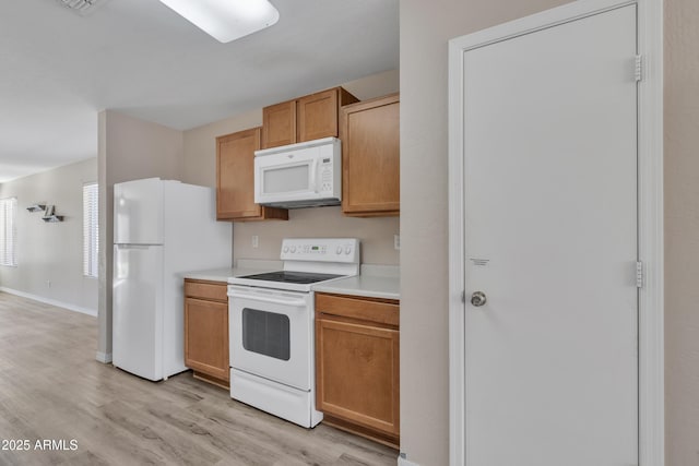 kitchen with white appliances, baseboards, light countertops, and light wood-style floors