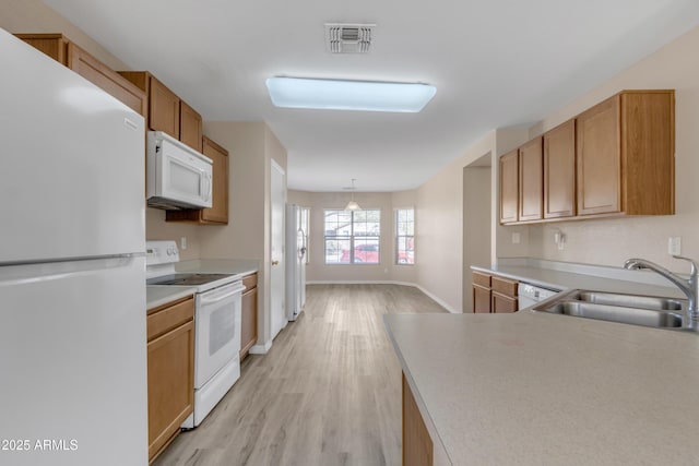 kitchen featuring light wood finished floors, visible vents, light countertops, white appliances, and a sink