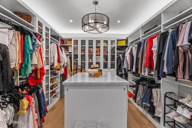 walk in closet with light hardwood / wood-style floors and a notable chandelier