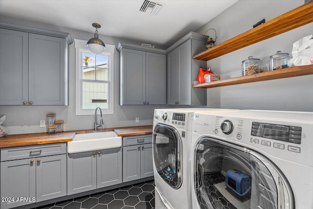 clothes washing area featuring cabinets, independent washer and dryer, dark tile patterned flooring, and sink