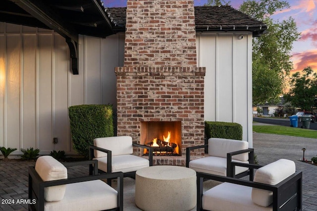 patio terrace at dusk featuring an outdoor brick fireplace