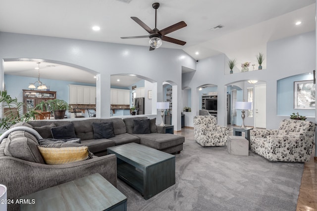 living room with ceiling fan with notable chandelier and high vaulted ceiling